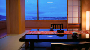 Habitación de tatami con mesa baja, sillas y vista al mar