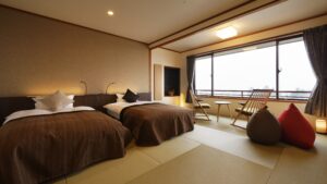 Tatami-Gästezimmer mit zwei Einzelbetten und Sitzbereich am Fenster