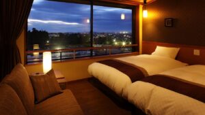 Zwei Einzelbetten neben einem großen Fenster bei Nacht
