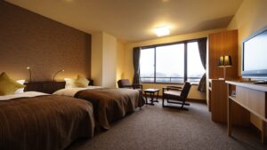 Zwei Einzelbetten in einem Gästezimmer mit Stühlen und Fenster