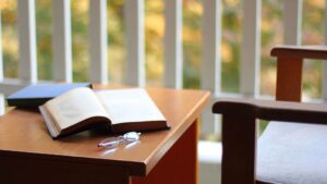 Table with open book beside a cushioned chair