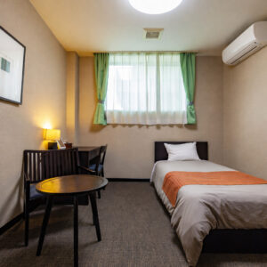 Lit simple à côté d’un bureau et d’une petite table dans la chambre