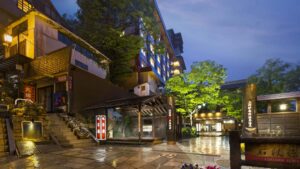 Entrada exterior de un ryokan por la noche con camino de piedra mojado