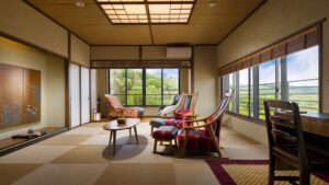 Habitación de tatami con sillas, mesa baja y escritorio junto a la ventana