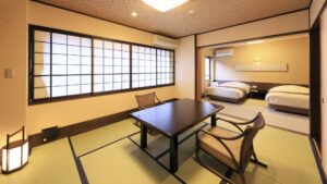 Habitación de tatami con mesa baja y sillas junto a las camas