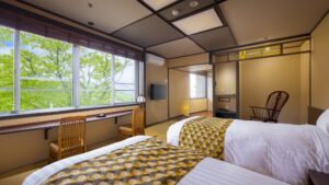 Camas individuales en una habitación de estilo tatami con asientos junto a la ventana