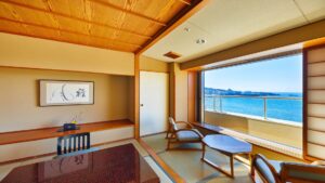 Camera in tatami con sedie, tavolo e finestra affacciata sull’oceano