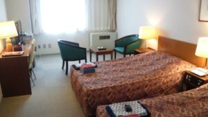 Twin beds in a guest room with chairs and desk