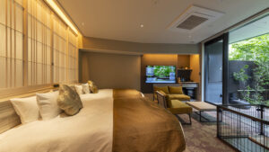 Schlafzimmer mit zwei Betten, Stühlen und großem Fenster