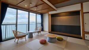 Habitación de tatami con sillas y mesas bajas junto a las ventanas