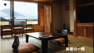 Habitación de tatami con mesa baja, cojines de suelo y ventana.