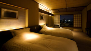 Zwei Betten in einem sanft beleuchteten japanisch eingerichteten Gästezimmer