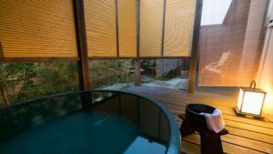 Private open-air bath beside a wooden deck and lantern