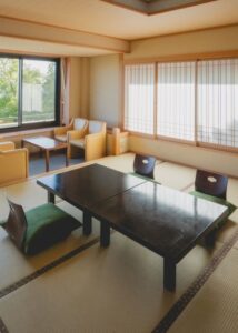 Chambre en tatami avec tables basses, chaises de sol et fauteuils