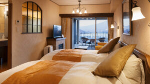 椅子のあるバルコニーと山の景色に面したツインベッド