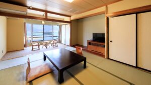 Camera in tatami con tavolo basso, sedie e vista dalla finestra