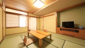 Camera in tatami con tavolo basso, sedie da pavimento e TV