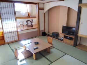 Camera in tatami con tavolo basso, sedie da pavimento e TV