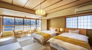 Lits jumeaux à côté d’une banquette près de la fenêtre dans une chambre en tatami