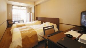 Two beds in a guest room with desk and chairs