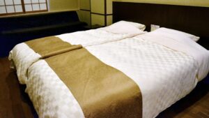 Two beds with beige runners in a guest room