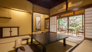 Tatamizimmer mit niedrigem Tisch und Stühlen am Garten.
