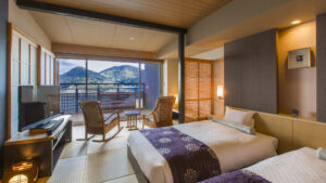 Twin beds in ryokan room with chairs and mountain view