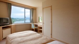 Cama junto a la ventana, escritorio y pequeño refrigerador