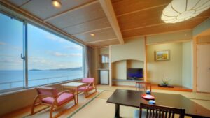 Habitación de tatami con sillas, mesa baja y ventana con vista al océano