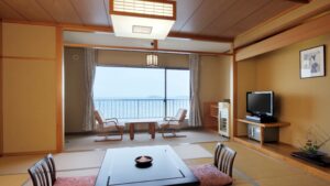 Habitación de tatami con mesa baja, sillas y ventana con vista al mar
