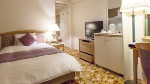 Chambre avec lit, lampe de chevet, télévision et armoire