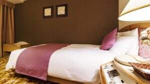 Lit double avec chemin de lit violet et lampe de chevet