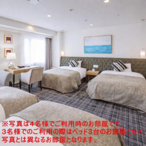 Chambre avec trois lits et un coin bureau