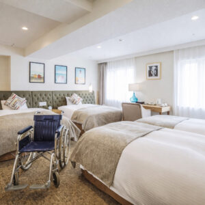 Trois lits dans une chambre avec fauteuil roulant