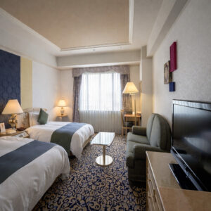 Lits jumeaux dans une chambre avec chaises et télévision