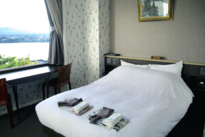 Bett mit gefaltetem Yukata neben Fenster und Schreibtisch