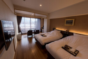 Zwei Einzelbetten in einem Gästezimmer mit Sitzplätzen am Fenster