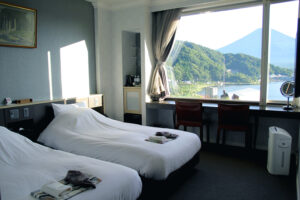 Zwei Betten neben einem Fenster mit Blick auf Berge und Wasser