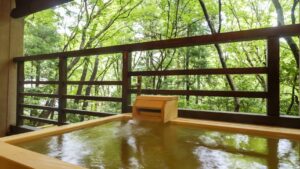 Private open-air wooden bath facing green trees