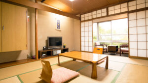 低いテーブルと窓際の椅子がある畳の部屋
