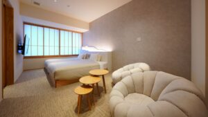 Schlafzimmer mit Bett, Loungesessel und kleinen Tischen