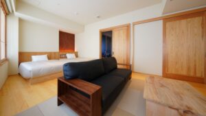 Schlafzimmer mit zwei Betten und schwarzem Sofa