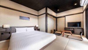 Bed in tatami guest room with low table and TV