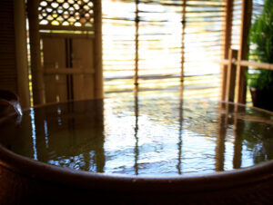 Round wooden bath filled with water by window