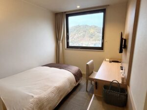 Einzelbett neben Schreibtisch und Fenster mit Bergblick
