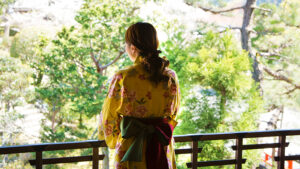Person im Yukata steht auf dem Balkon mit Blick auf den Garten