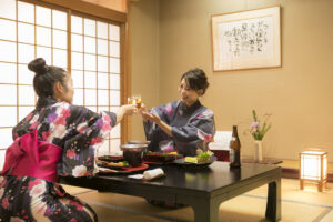 Zwei Frauen in Yukata beim Essen an einem niedrigen Tisch