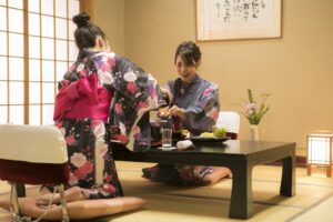 Zwei Frauen in Yukata sitzen an einem niedrigen Tisch