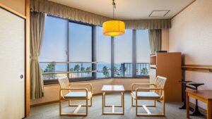 Zwei Stühle und ein Tisch am Fenster mit Meerblick