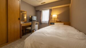 Einzelbett neben Schreibtisch und Fenster im Gästezimmer